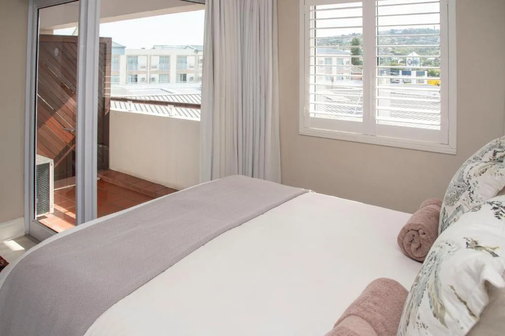 Bright bedroom with bed, balcony doors, and town views from Knysna