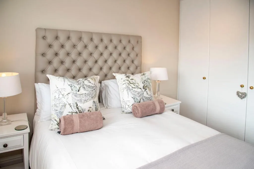 Modern bedroom with upholstered headboard, white bedding, and decorative pillows