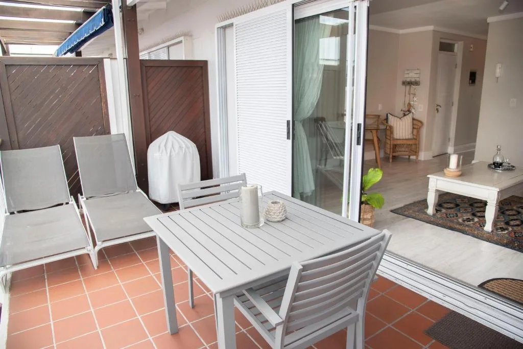 Outdoor patio with dining table, loungers, and garden access doors