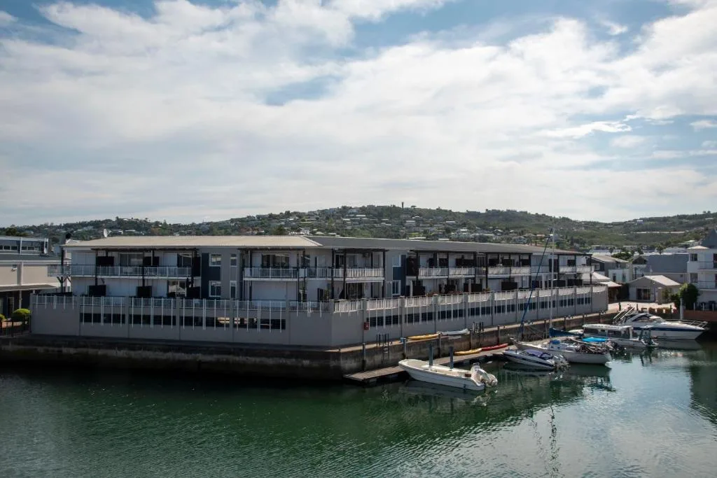 Modern waterfront apartment building with boats docked in lagoon below
