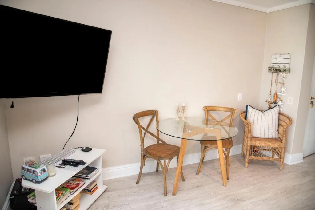Modern lounge with flat-screen TV, round glass table, and wicker chairs