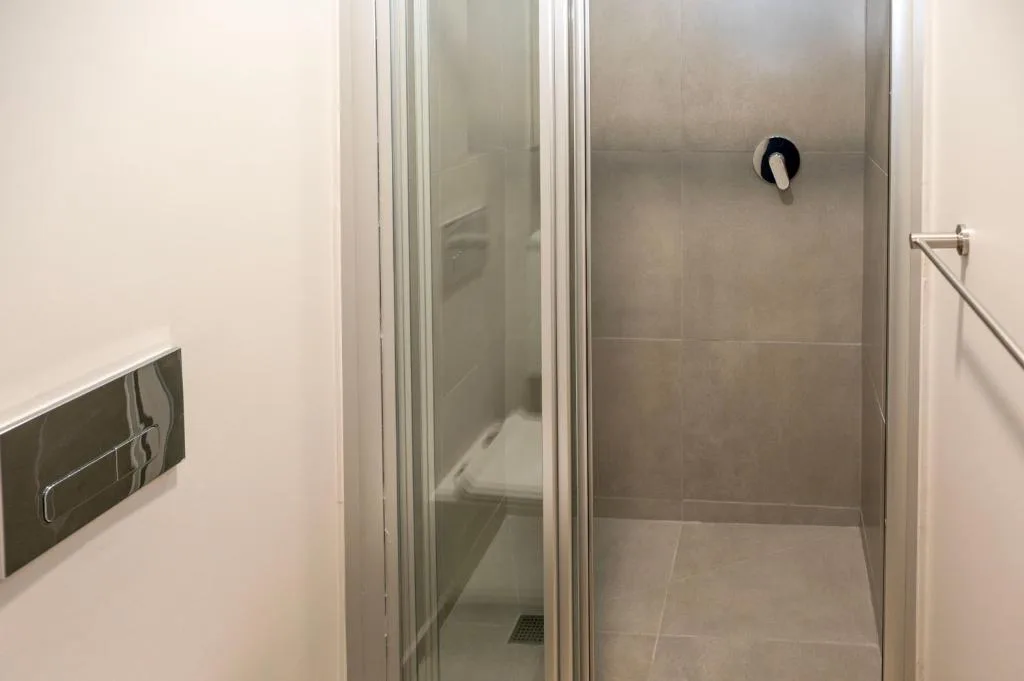 Modern shower enclosure with glass doors and neutral tile walls