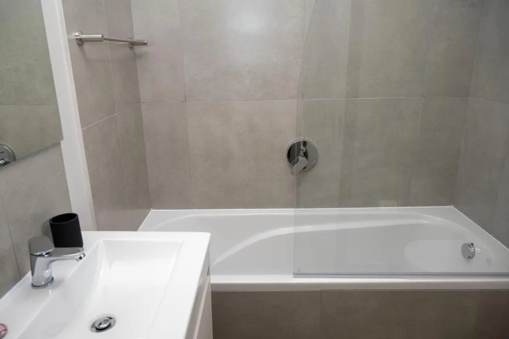Modern bathroom with white sink, bathtub, and tiled shower enclosure