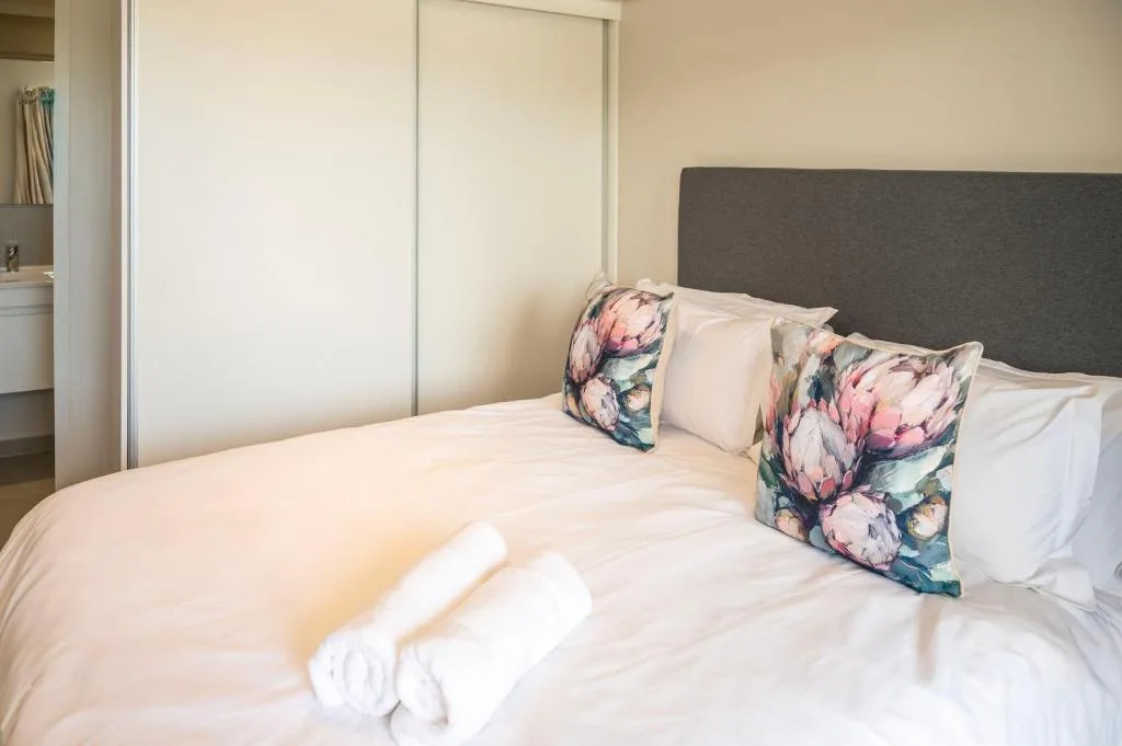 Neatly made bed with floral cushions and rolled white towels