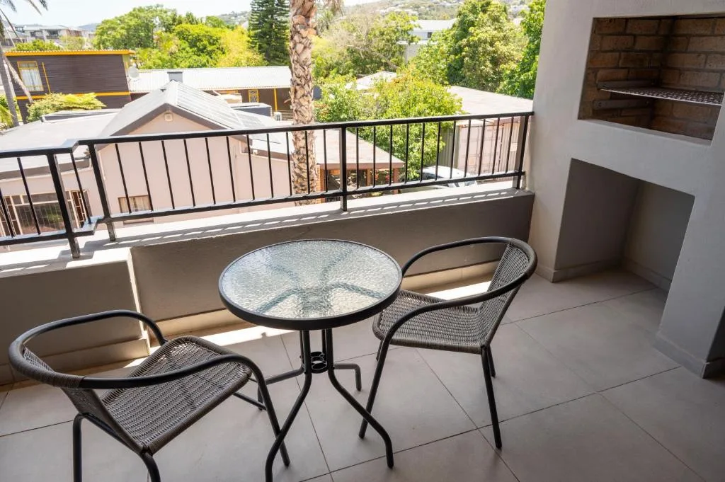 Outdoor balcony with seating area overlooking lush green surroundings