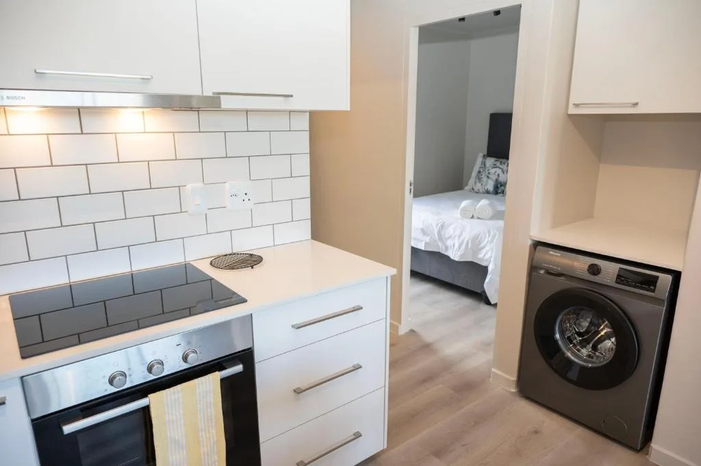 Modern kitchen with stove, white cabinetry, subway tile backsplash, and washing machine