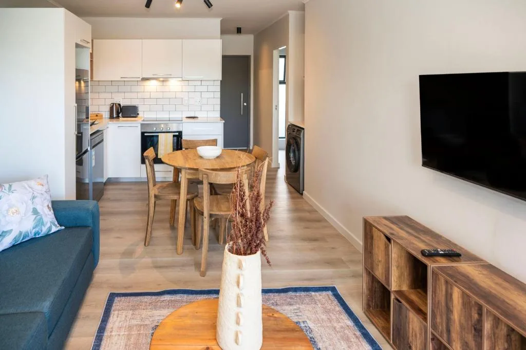 Open-plan living area with sofa, TV, dining table, and modern kitchen