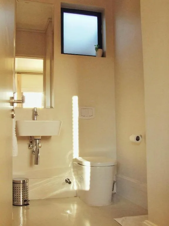 Modern bathroom with rectangular sink, toilet, and high window