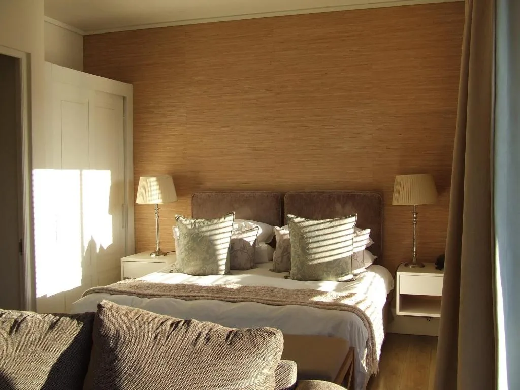 Spacious bedroom with brown upholstered bed and cream pillows, warm wood paneling