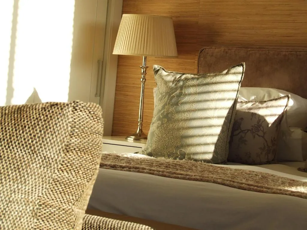 Luxury bedroom with wooden headboard, decorative pillows, and bedside lamp