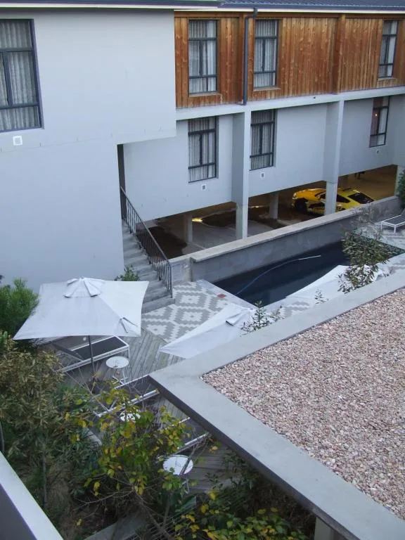 Modern white apartment building with wooden upper facade and shaded carport below