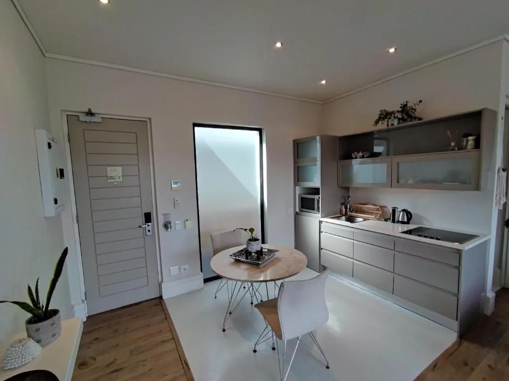 Modern kitchen with dining area, stainless steel appliances, and light wood flooring