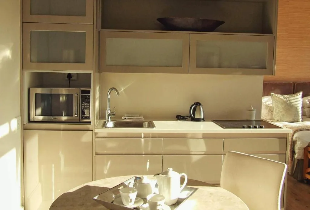 Cream kitchen with microwave, sink, cooktop, and glass-fronted cabinetry