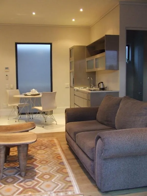 Modern lounge with gray sofa, wooden table, and open-plan kitchen area