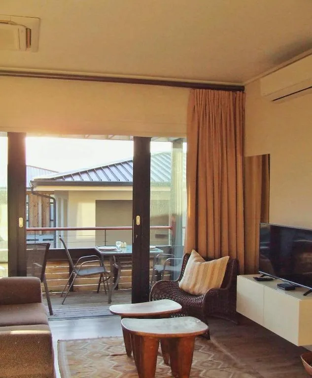 Warm lounge area with TV, sofa, and open deck access through glass doors
