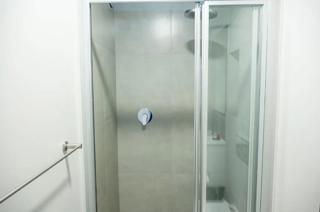 Modern shower enclosure with glass doors and overhead showerhead
