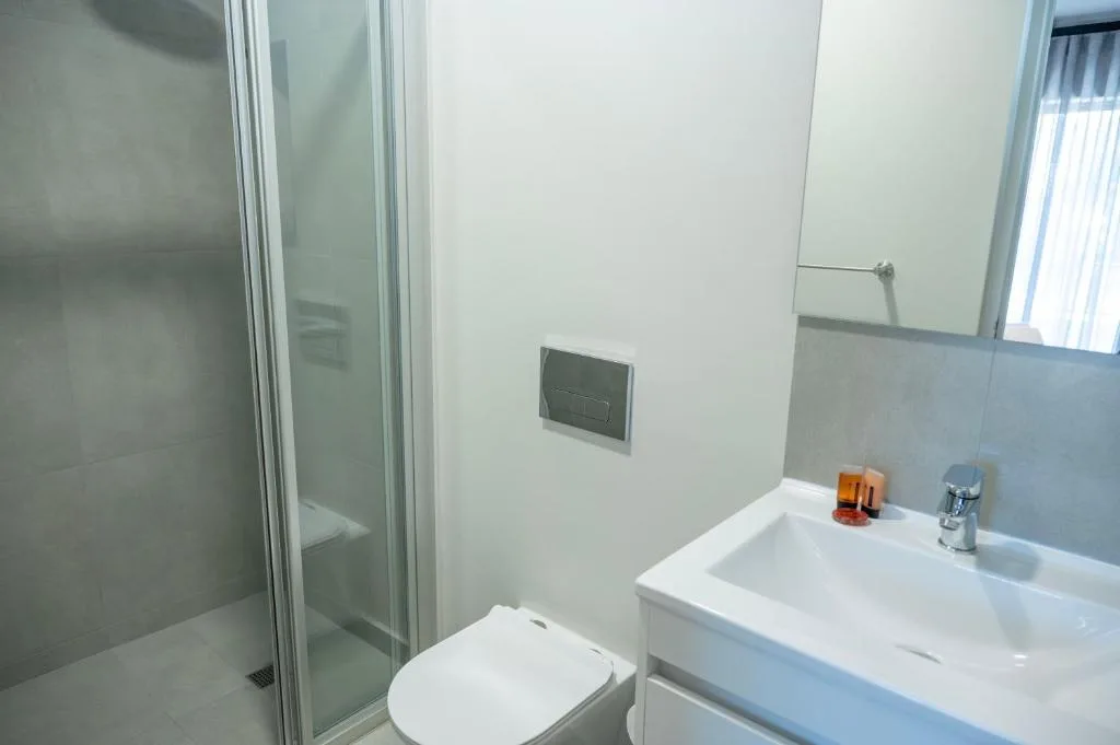 Modern bathroom with shower enclosure, white vanity sink, and toilet