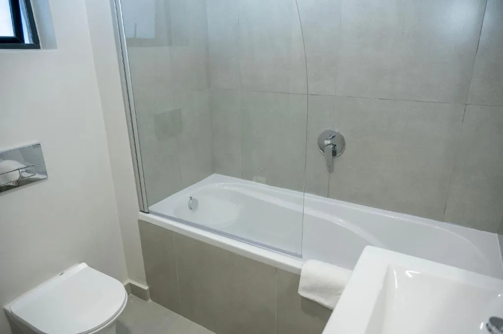 Modern bathroom with bathtub, glass shower screen, and white toilet