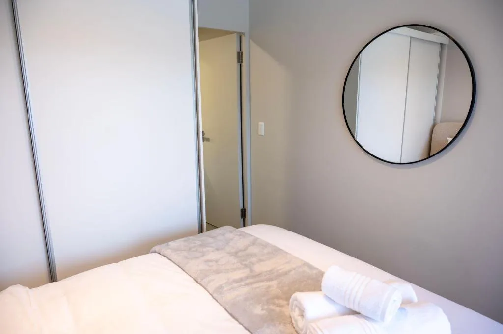 Bright bedroom with queen bed, round mirror, and modern wardrobe closet