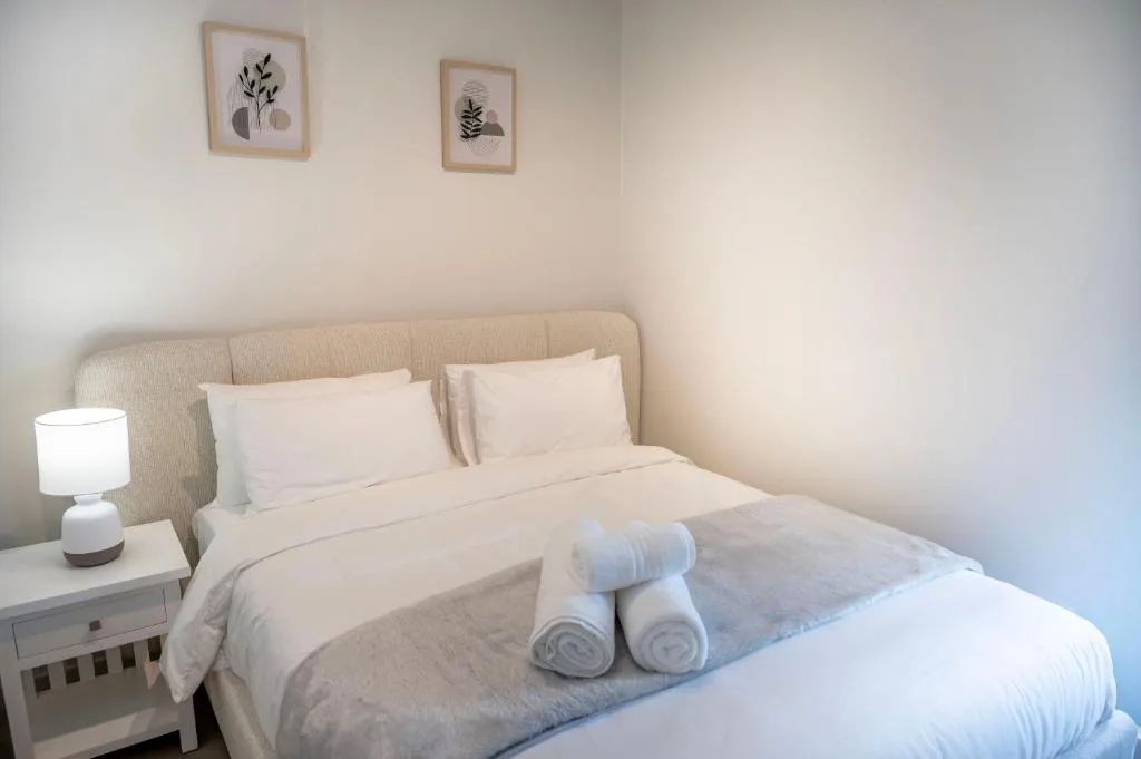 Bright bedroom with neutral tones, bed, bedside lamp, and botanical wall art