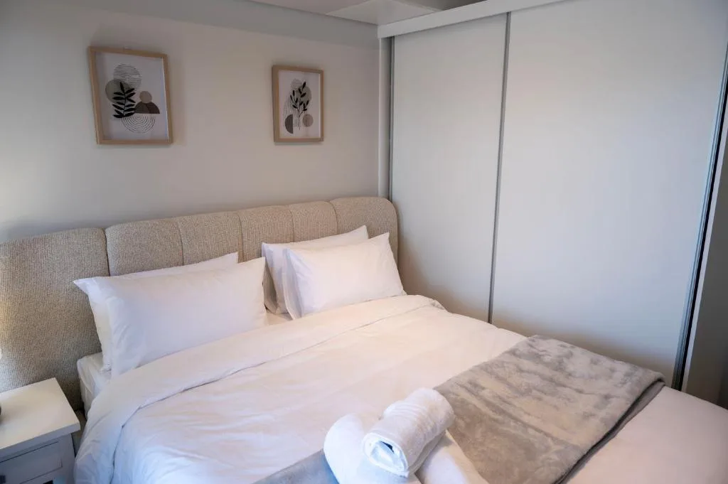 Spacious bedroom with queen bed, upholstered headboard, minimalist wall art