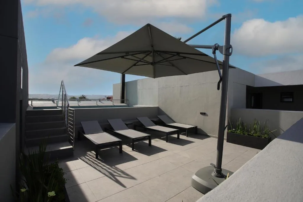 Rooftop patio with loungers, cantilever umbrella, and mountain views