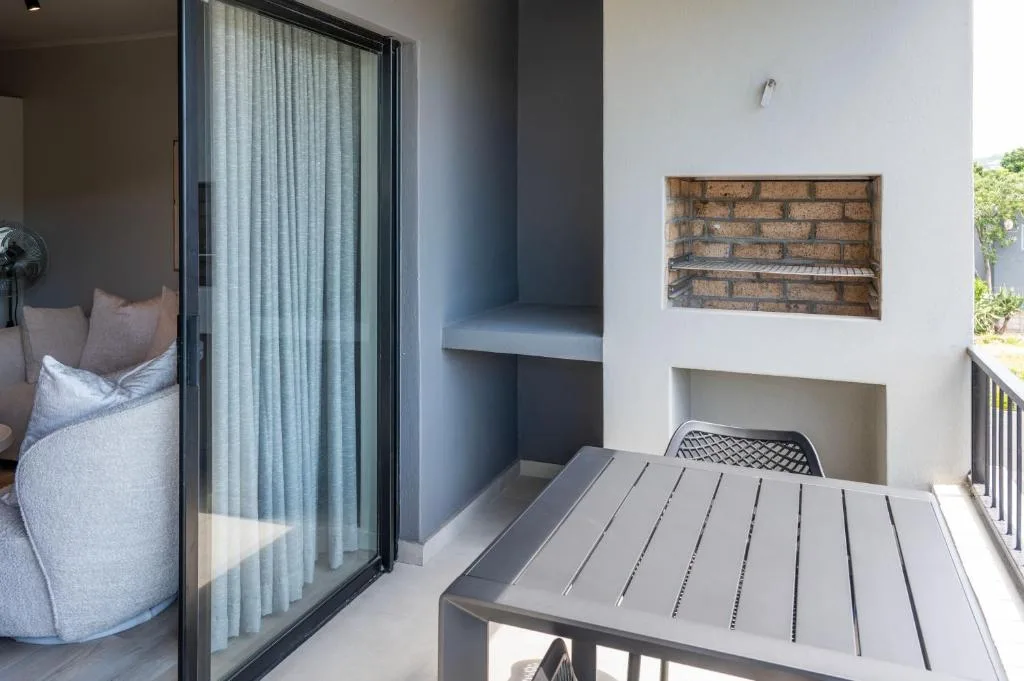 Modern outdoor deck with dining table overlooking garden and home interior