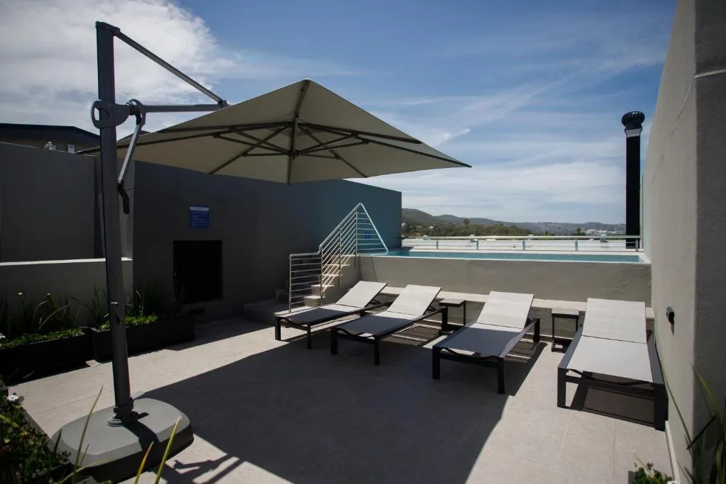 Rooftop terrace with loungers, umbrella, and mountain views beyond