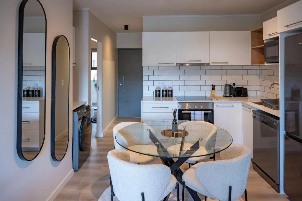 Modern kitchen with white cabinetry, subway tile backsplash, and integrated dining area