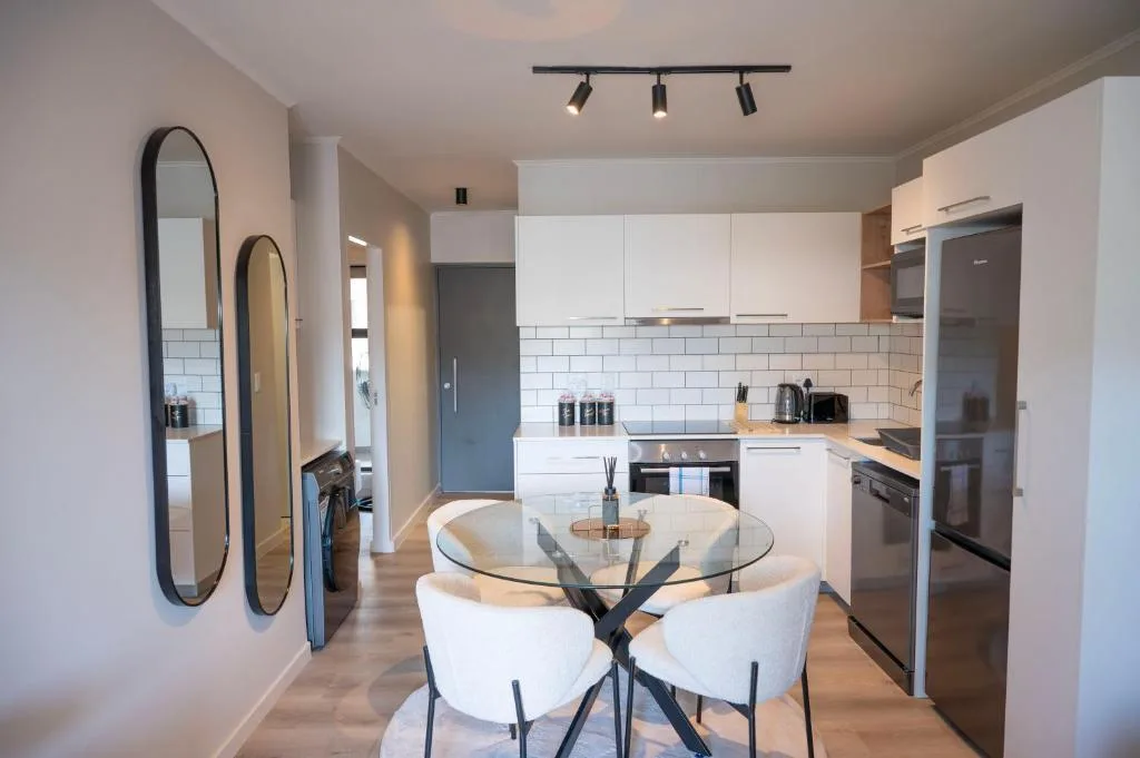Modern white kitchen with dining table, stove, and subway tile backsplash