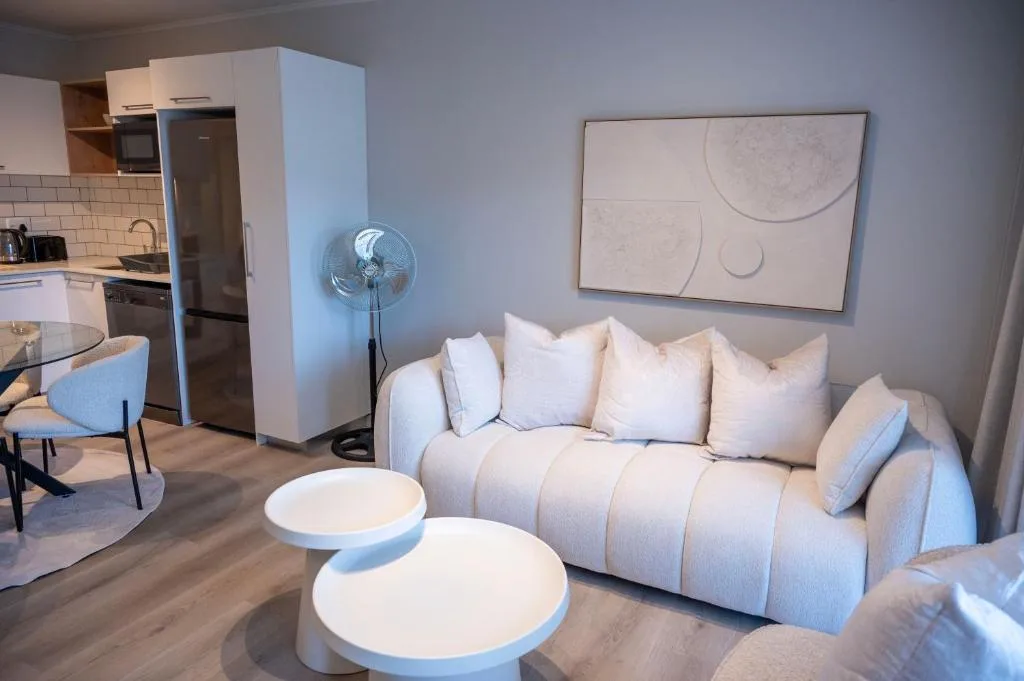 Modern lounge with cream sofa, round coffee tables, and kitchen area visible