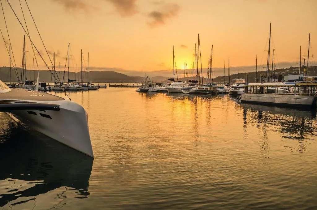 Golden sunset over Knysna harbor with sailboats and mountains