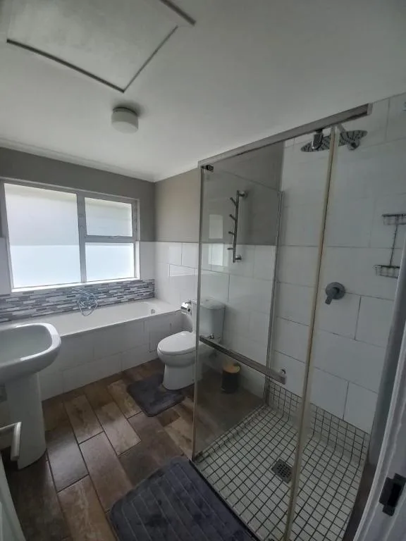 Modern bathroom with walk-in shower, vanity, and ocean view window
