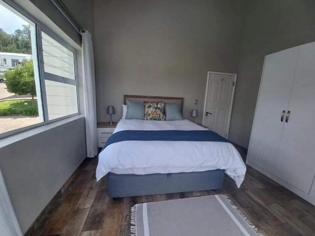 Spacious bedroom with queen bed, white bedding, blue stripe, and garden views