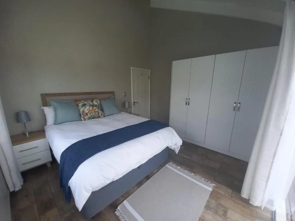 Modern bedroom with queen bed, white bedding, blue runner, and built-in wardrobe