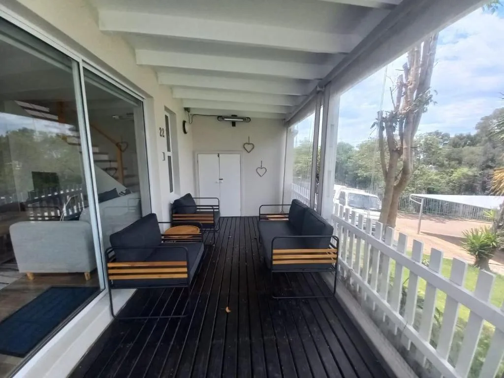 Covered deck with black striped flooring and cushioned seating overlooking gardens