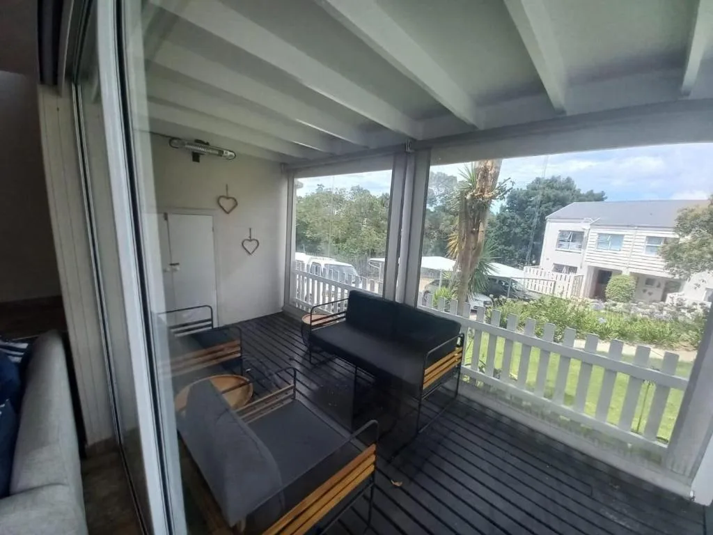 Covered deck with black furniture overlooking neighboring properties and garden views