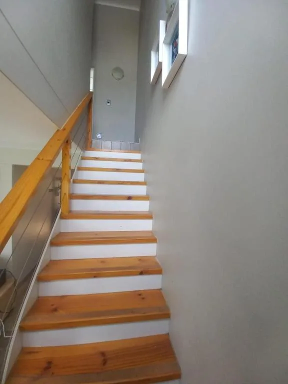 Wooden staircase with white risers and natural wood handrail in bright interior
