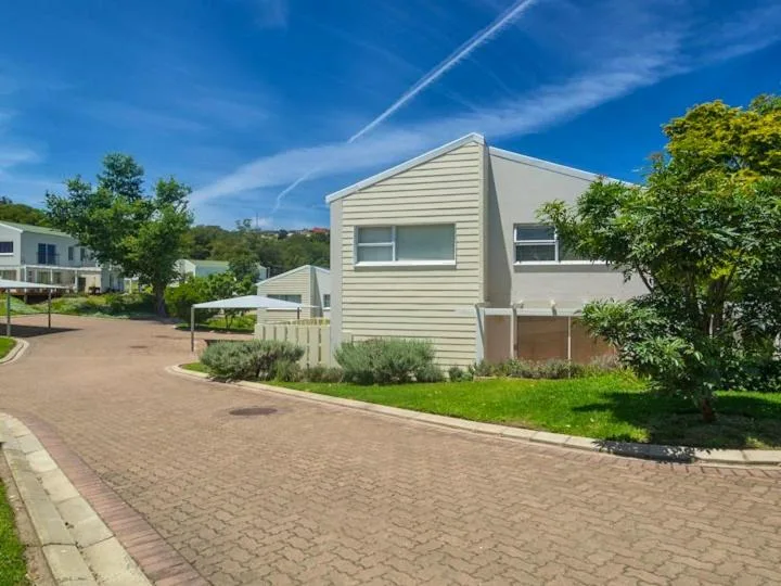 Modern white holiday home with brick driveway and manicured gardens