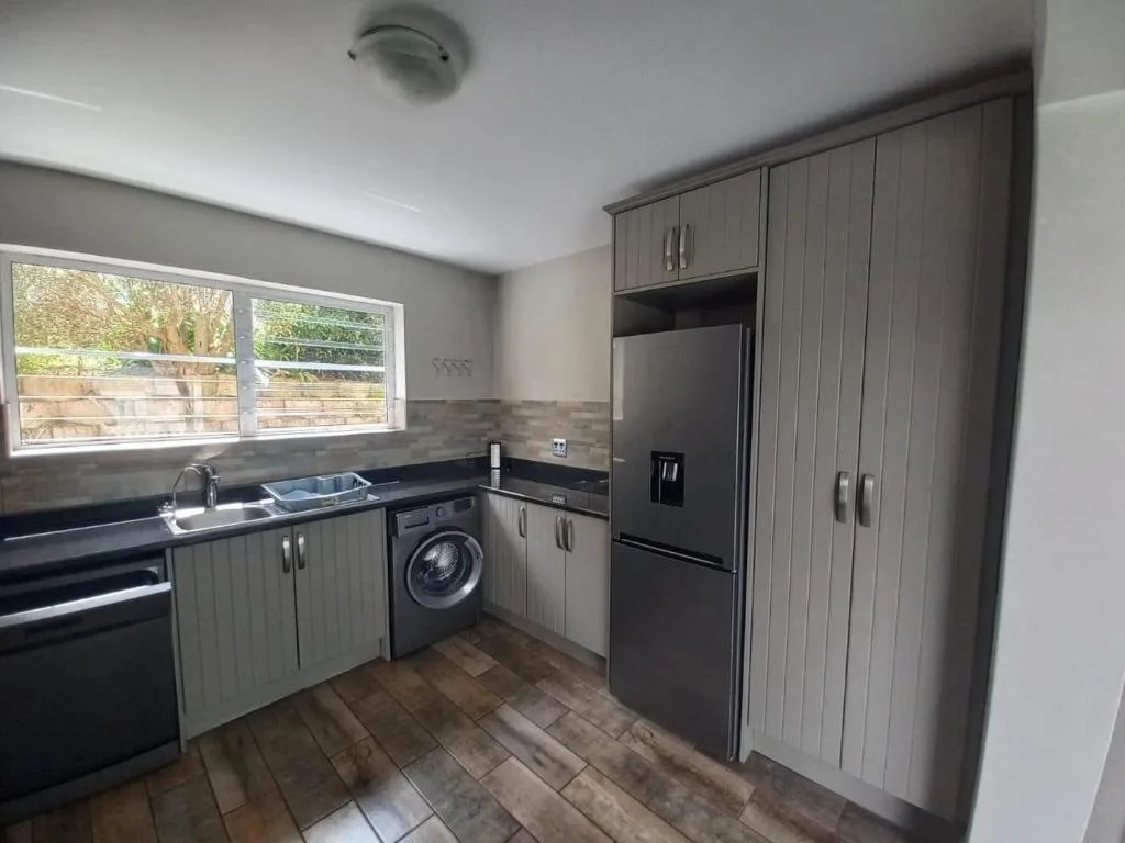 Modern kitchen with gray cabinetry, black appliances, and large window