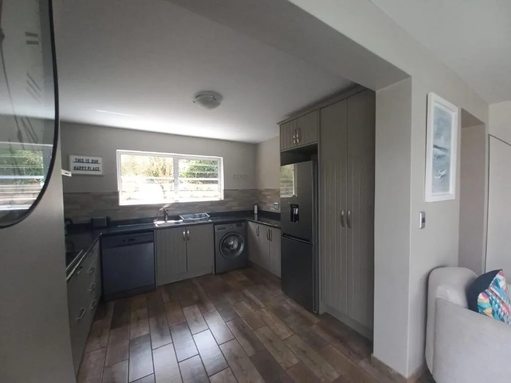 Modern kitchen with dark cabinetry, stainless steel appliances, and window views