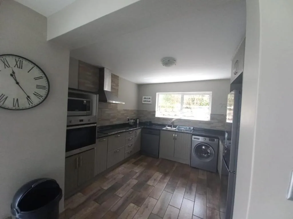 Modern kitchen with stainless steel appliances, dark cabinetry, and wooden flooring