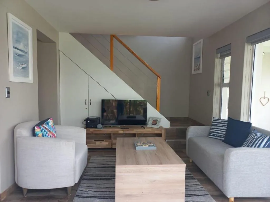 Modern open-plan lounge with grey sofas, wooden coffee table, and TV entertainment unit