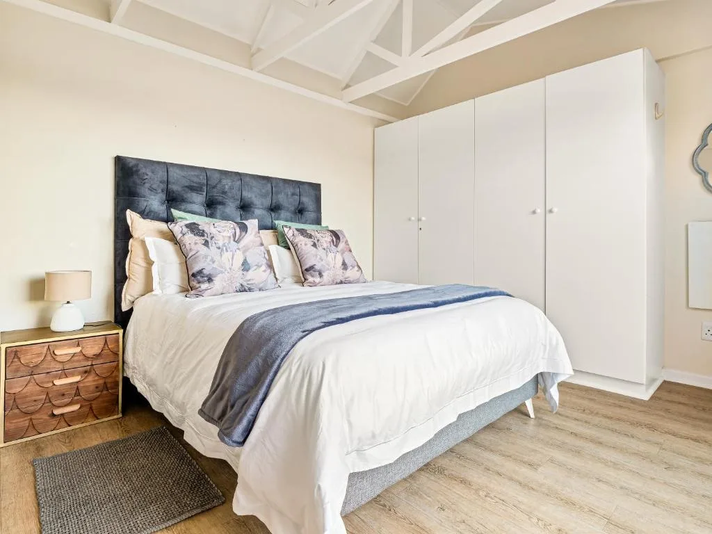 Spacious bedroom with queen bed, dark headboard, white wardrobe, wooden nightstand