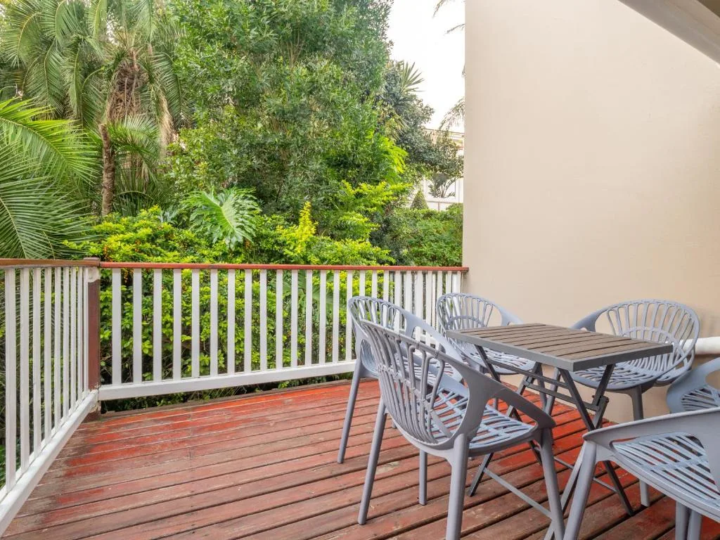 Wooden deck with dining table and chairs overlooking lush garden