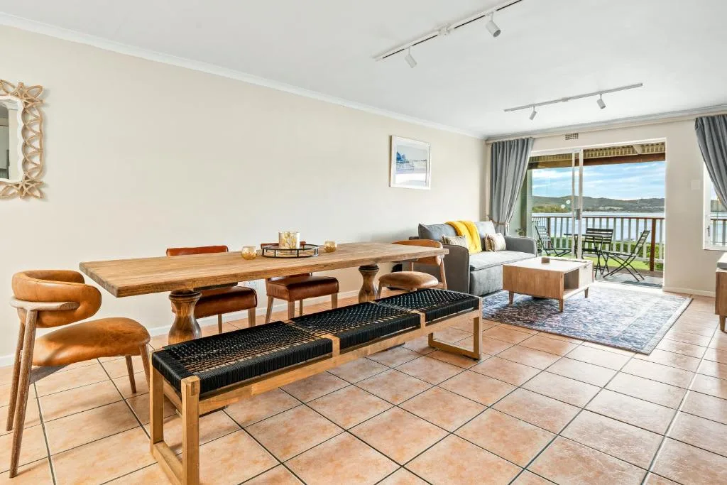 Open-plan dining and lounge area with wooden table and scenic view doors