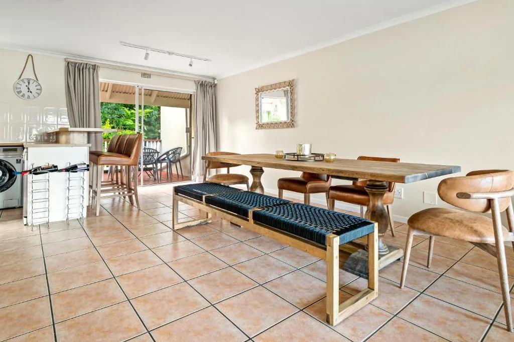 Open-plan dining area with wooden table, bench seating, and kitchen visible