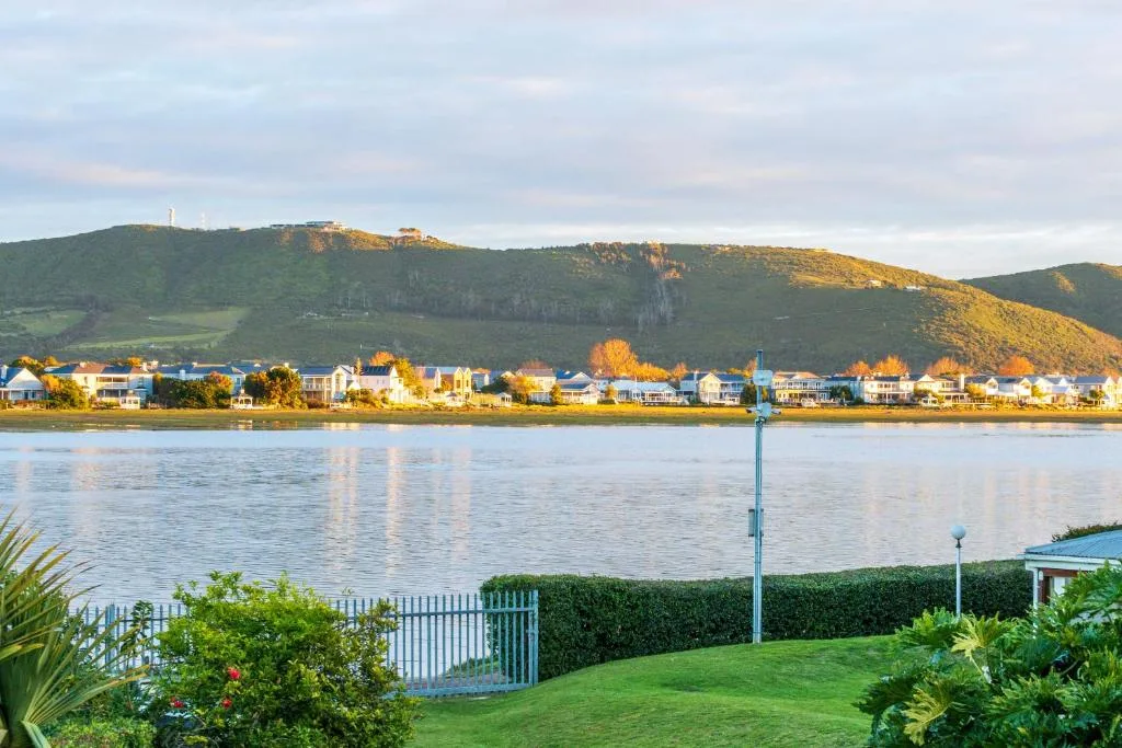 Scenic lagoon view with mountains, town, and manicured garden in foreground