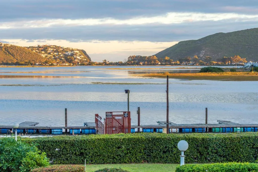 Scenic lagoon view with forested hills and moored boats at sunset