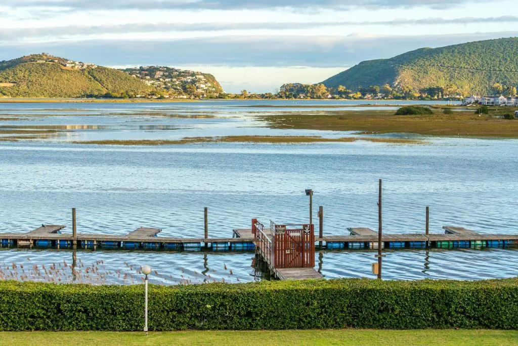 Knysna Heads lagoon with forested mountains and wooden jetty beyond